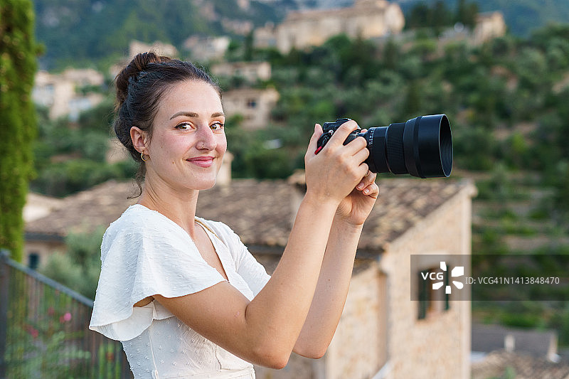 一个年轻的女人用相机拍照，看着相机。旅游的概念图片素材