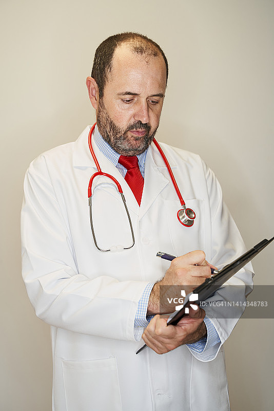 严肃的白人英俊男医生的肖像在白色背景上做笔记。医疗保健和医学理念。图片素材