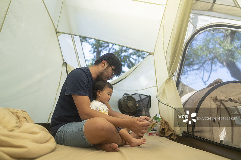 露营时间父亲花时间教和玩绘本与女儿在帐篷户外生活方式周末活动图片素材