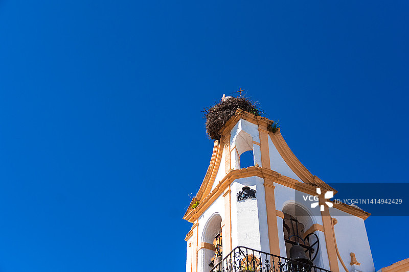 在西班牙安达卢西亚加的斯的Chiclana de la Frontera，一只鹳在钟塔顶部筑巢。图片素材