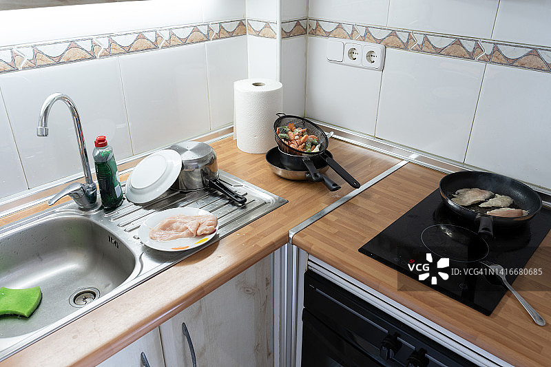 厨房正在用一个煎锅和一个装满蔬菜的滤锅烹饪鸡肉图片素材