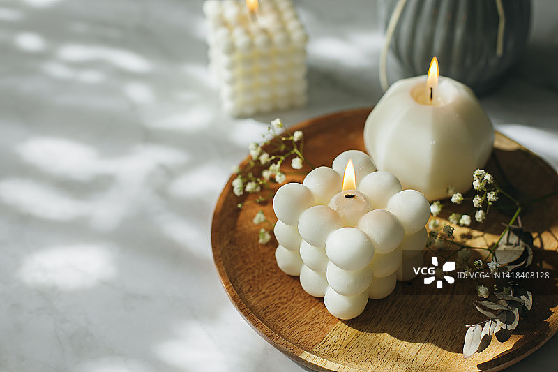 三个白色的babble燃烧的蜡烛的背景与阳光的阴影图片素材