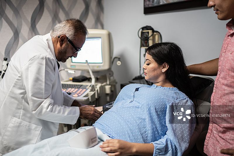 产科医生在医院的办公室里给怀孕的中年妇女量血压图片素材
