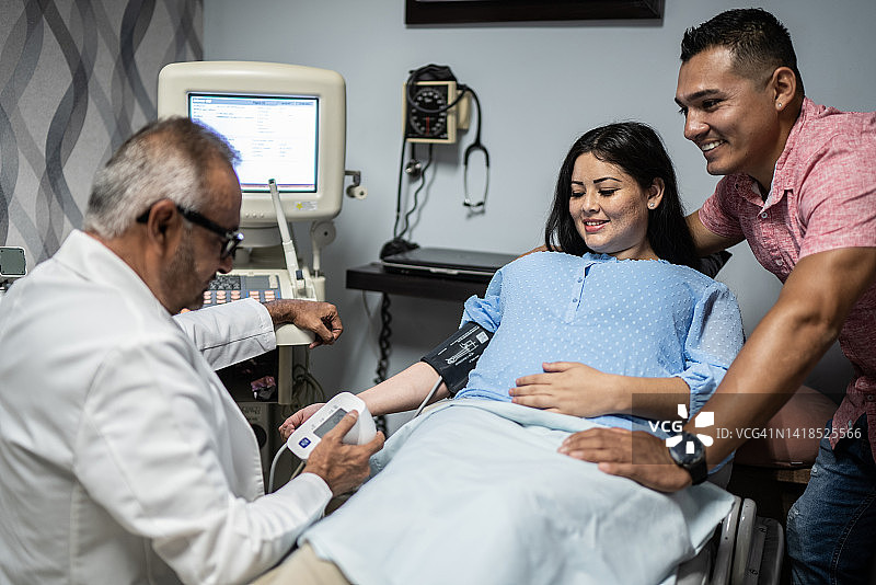 产科医生在医院的办公室里给怀孕的中年妇女量血压图片素材