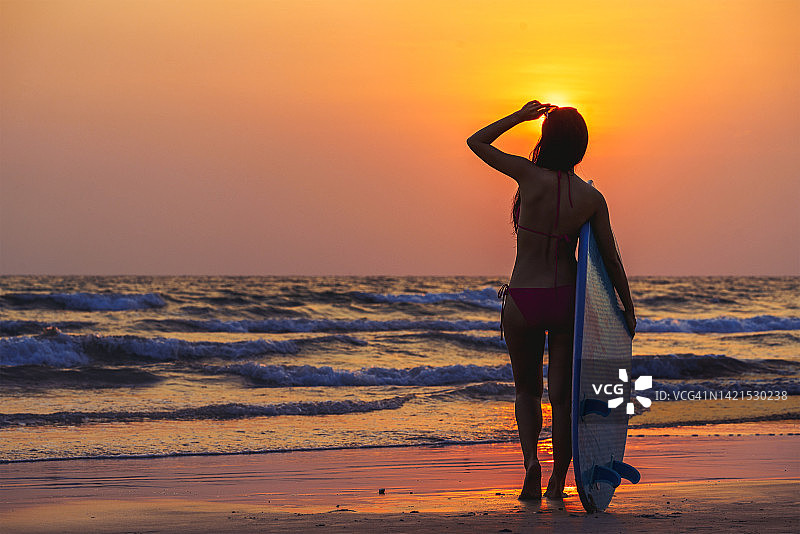 在温暖阳光明媚的夏天，冲浪女孩们拿着冲浪板站在海边。图片素材