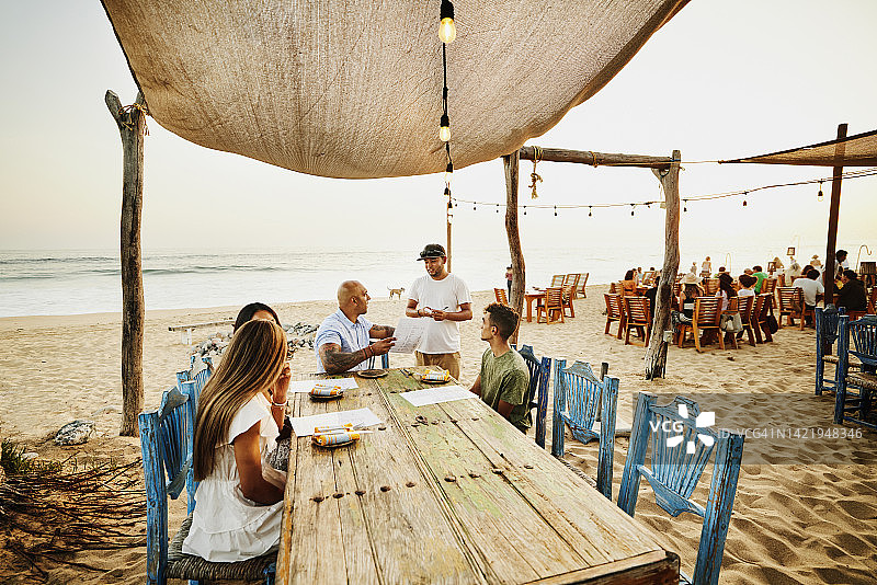 服务员在海滩餐厅为家人点菜的广角镜头图片素材