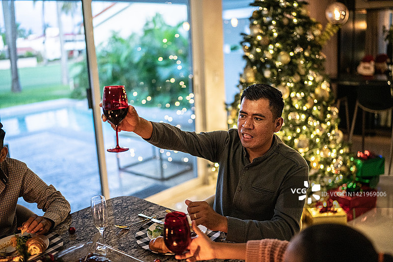 中年男子在家中的餐桌上与家人举杯庆祝圣诞节图片素材