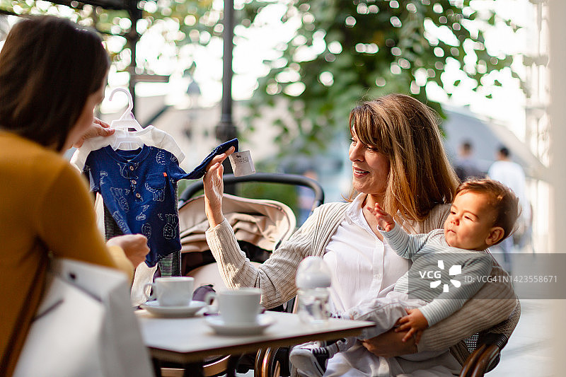 年轻女子与她的母亲和她的男婴在咖啡馆享受户外图片素材