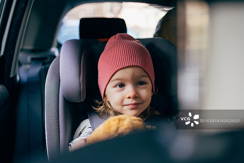 一个可爱的小女孩拿着她最喜欢的玩具，开车旅行的肖像图片素材