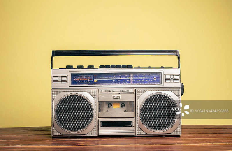 复古便携式立体声录音机在木制桌子与黄色背景。图片素材