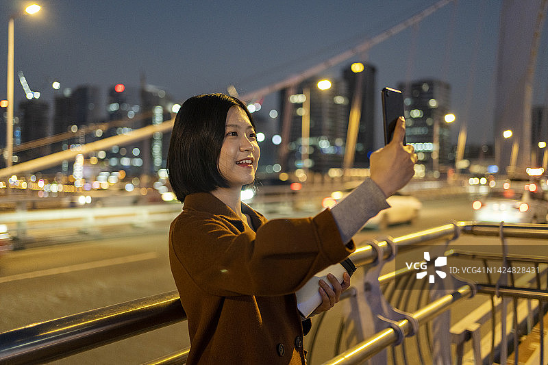 亚洲妇女在通勤途中用手机拍照图片素材
