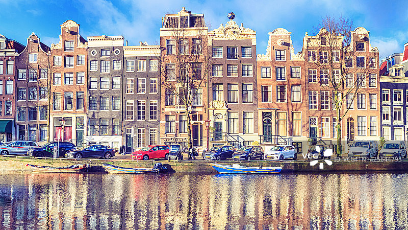 在一个阳光明媚的冬日的城市景观-在阿姆斯特丹历史悠久的中心看房子和城市水道的船图片素材