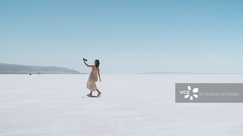 年轻的女游客和社交媒体影响者在盐湖城的白色盐上旅行时自拍和视频博客Türkiye图片素材