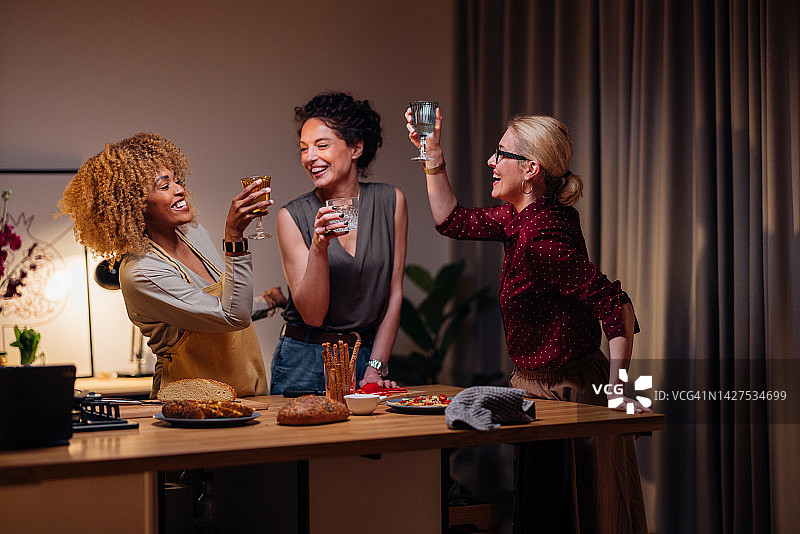 三个女人在准备晚餐时用一杯酒敬酒图片素材