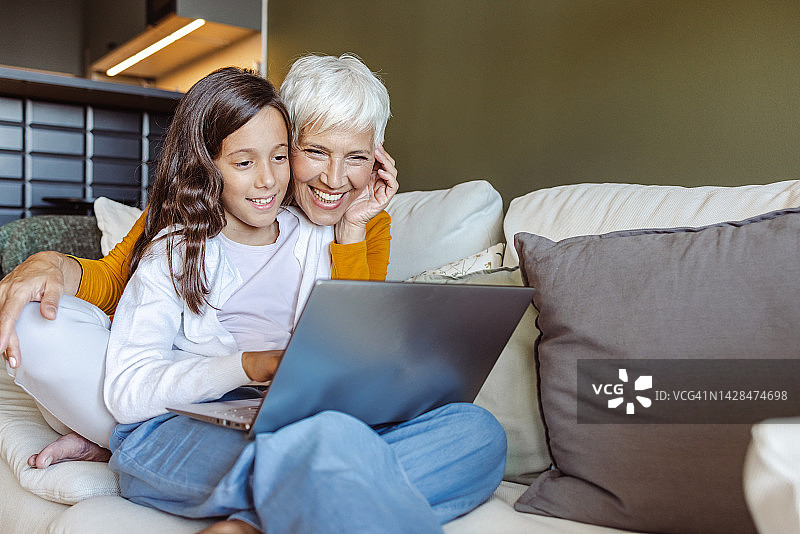 奶奶和她的孙女在家里用笔记本电脑上网图片素材