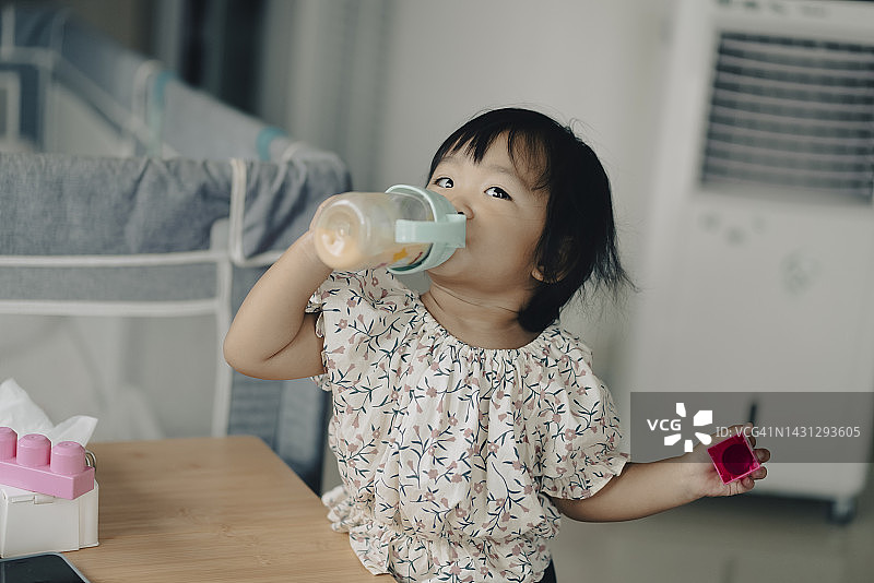 亚洲女婴喜欢在家里用奶瓶喝牛奶图片素材