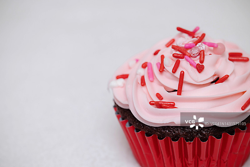 情人节巧克力小蛋糕配粉色糖霜和红色糖屑图片素材