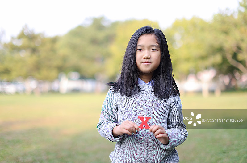 手持字母“X”的小女孩图片素材