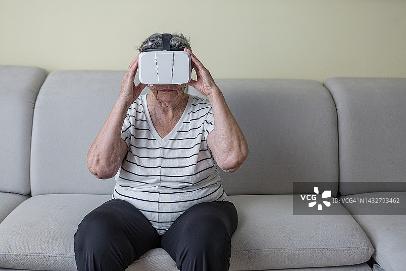 严肃的老妇人戴着VR眼镜体验虚拟现实图片素材
