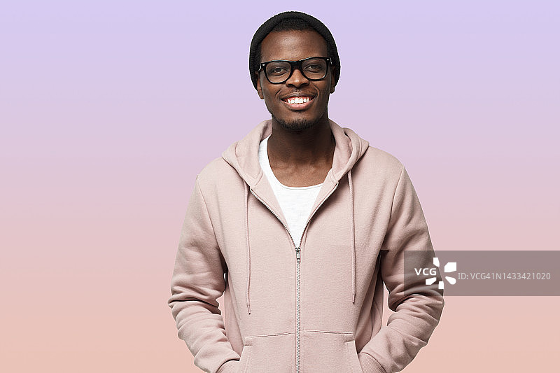 肖像微笑英俊的非裔美国人在粉色卫衣孤立地站在紫色图片素材