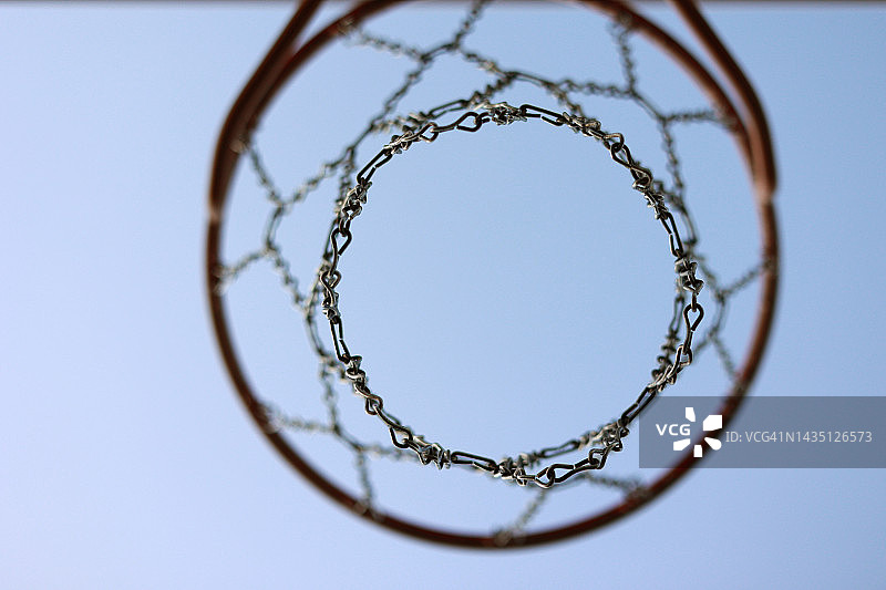 蓝色天空背景的金属网和木制篮板篮球框。在户外篮球场。露天街球场上的休闲运动设备，街道上的游乐场。底视图图片素材