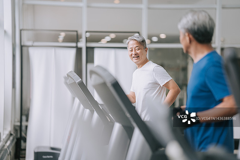 两名中国老人一起在健身房的跑步机上跑步图片素材