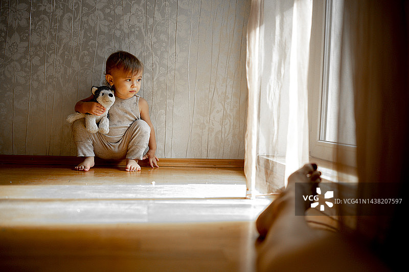 男孩拿着毛绒玩具在家里蹲着图片素材