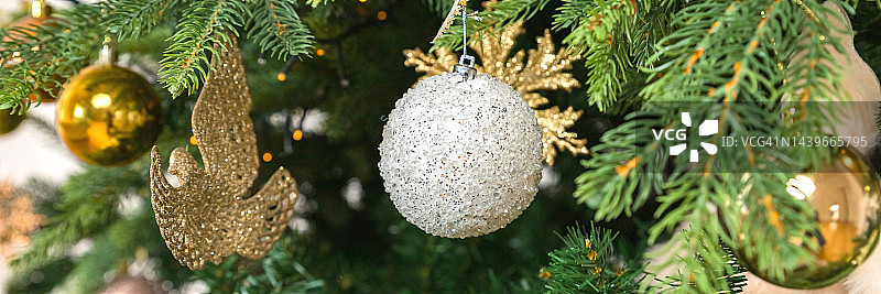 圣诞装饰。白色和金色的球挂在松树树枝上的圣诞树，花环和装饰品。用复古风格庆祝圣诞季。新年快乐。网络横幅图片素材