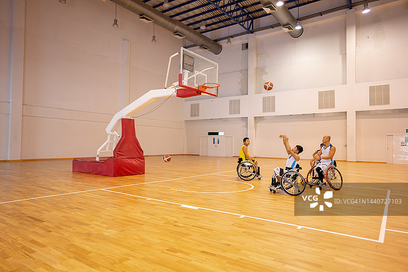 适应性运动员坐在轮椅上在篮球场上投篮。图片素材
