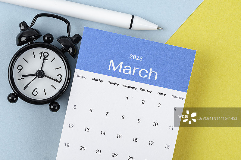 日历桌2023:3月是组织者用闹钟和双色纸背景白笔做计划和截止日期的月份。图片素材