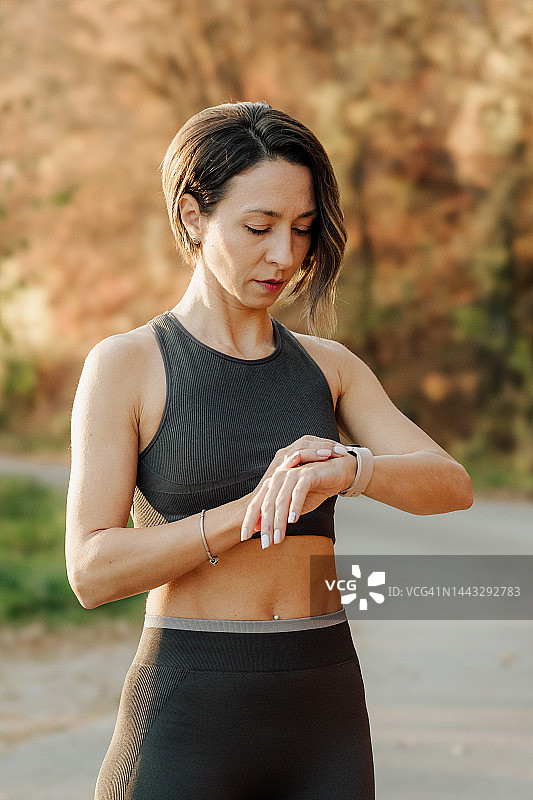 运动的年轻女子在锻炼时使用智能手表图片素材
