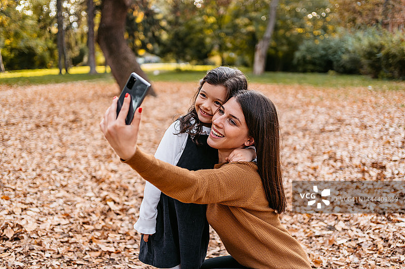 秋天，母亲和女儿在公园里自拍图片素材