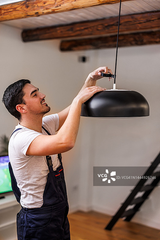 一位年轻的维修工程师正在更换灯泡。图片素材