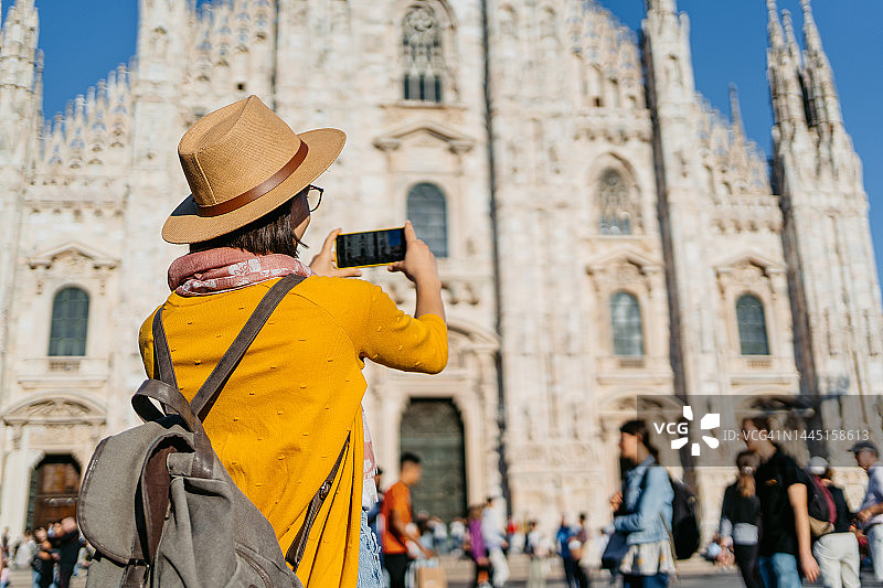 年轻的女游客在米兰的大教堂拍照图片素材
