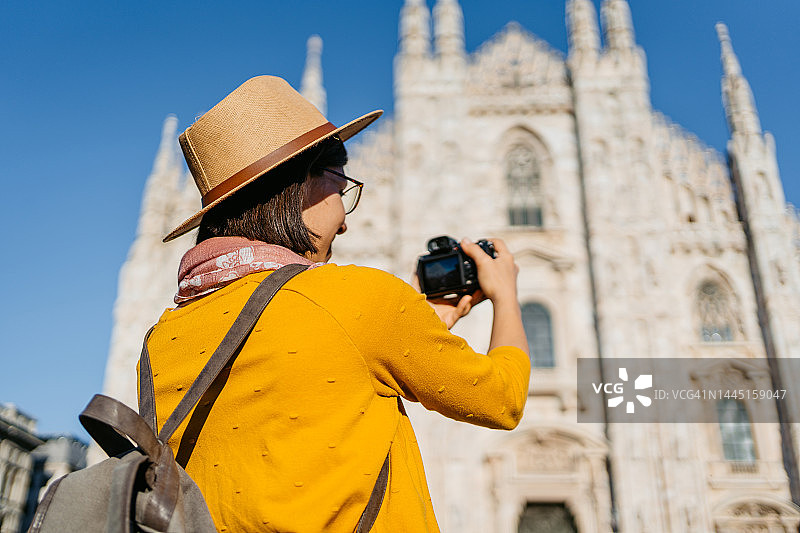 年轻的女游客在米兰的大教堂拍照图片素材