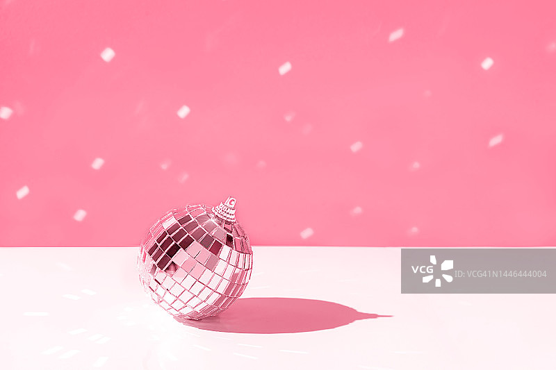 圣诞快乐，新年快乐。银色迪斯科球在柔和的红色Viva品红色2023年背景与雪。图片素材