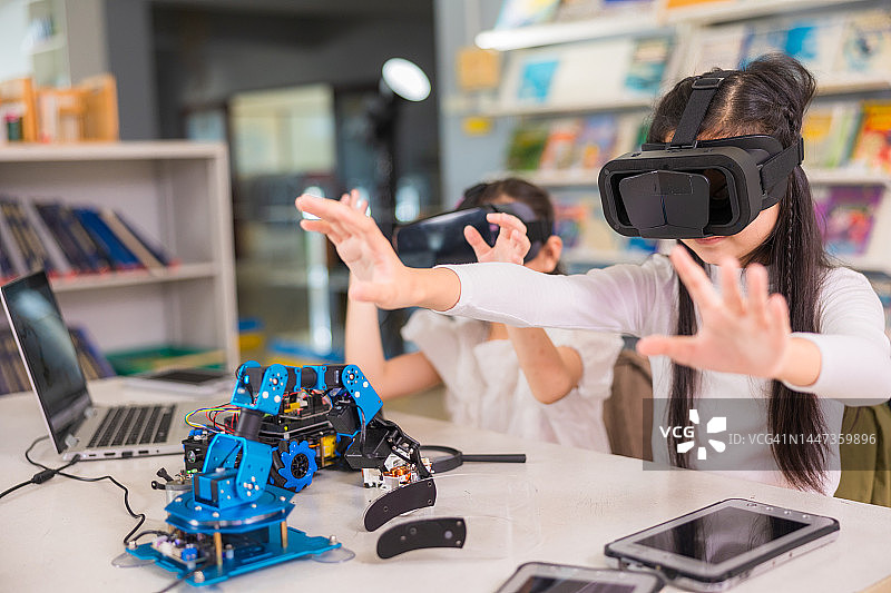 两名亚洲学生在教室里用VR眼镜学习机器人设计图片素材