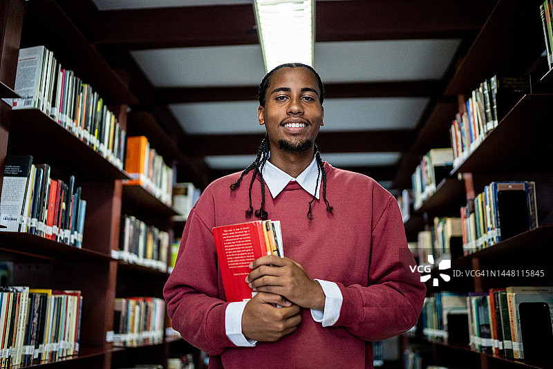 一个年轻人在图书馆里拿着一本书的肖像图片素材