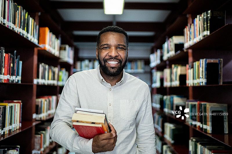 一个中年成年男子在图书馆拿着一本书的肖像图片素材