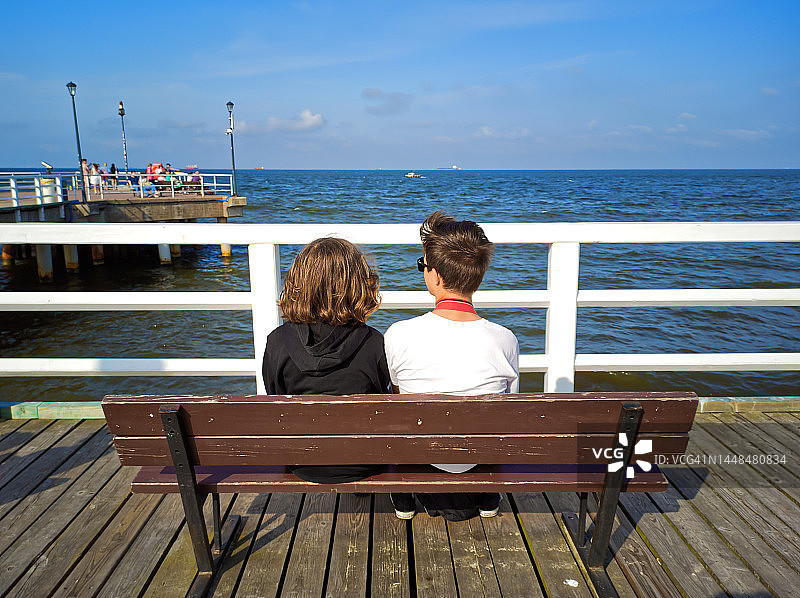 女孩和男孩坐在长凳上的背影图片素材