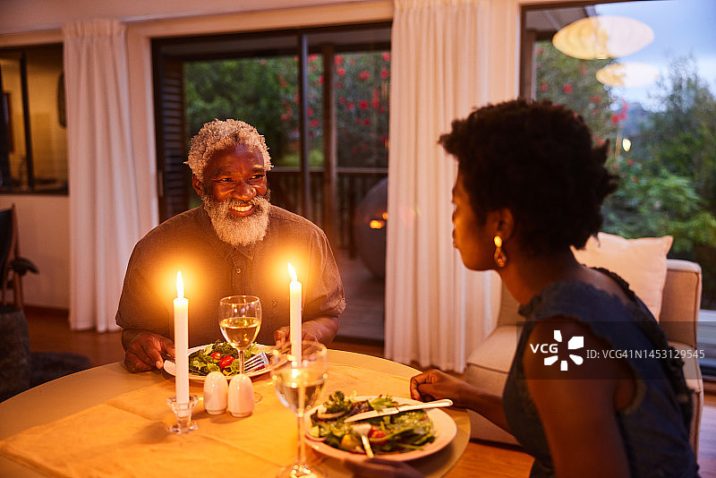 在家里的烛光晚餐上，微笑的男人和他的妻子交谈图片素材