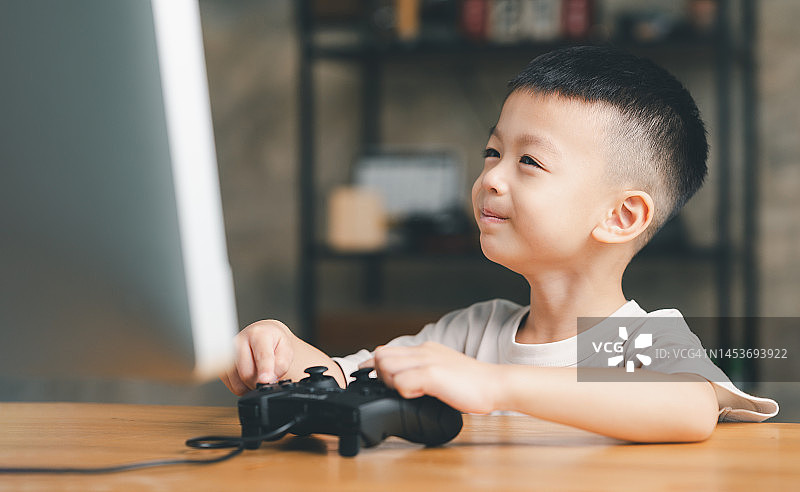 亚洲男孩，小孩，小孩玩电子游戏操纵杆。图片素材