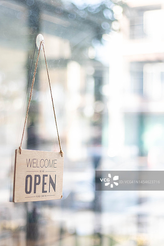 店面开门标志安装在店面前的玻璃门周围，让顾客可以看到店面开门标志，来咖啡店使用服务，启动经营理念。图片素材