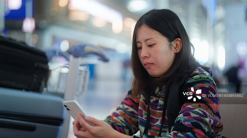 女游客在机场候机时使用智能手机图片素材