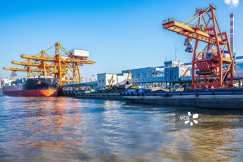 在长江沿岸的港口，有许多巨大的起重机和货船装卸货物。中国江苏省江阴市。图片素材