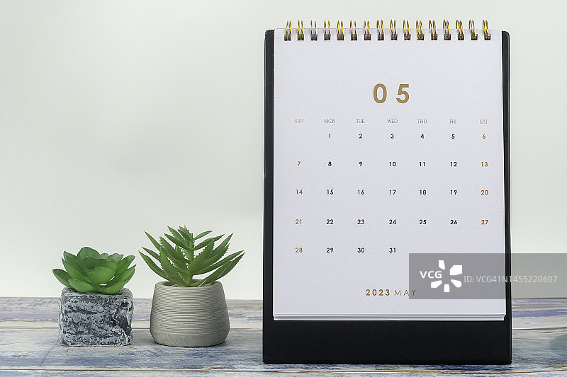 日历桌2023:5月是组织者计划和截止日期的月份，在浅灰黄色背景下放置室内植物。图片素材