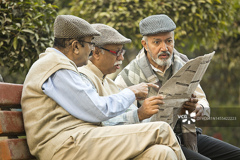 年长的男性朋友在公园看报纸图片素材