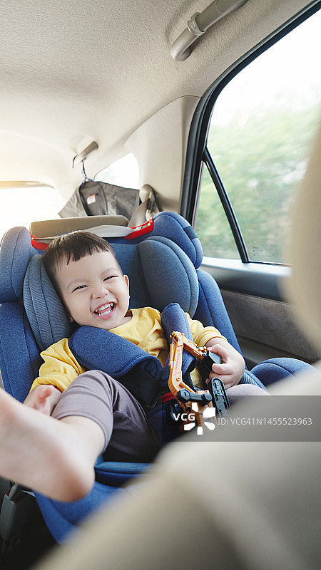 快乐微笑的亚洲小男孩坐在安全座椅上图片素材