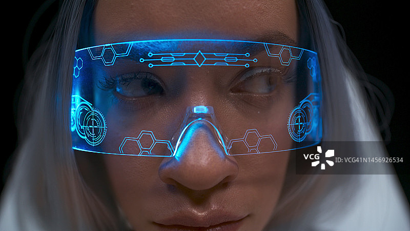 严肃的VR眼镜女孩脸部特写。女人用智能眼镜看图片素材