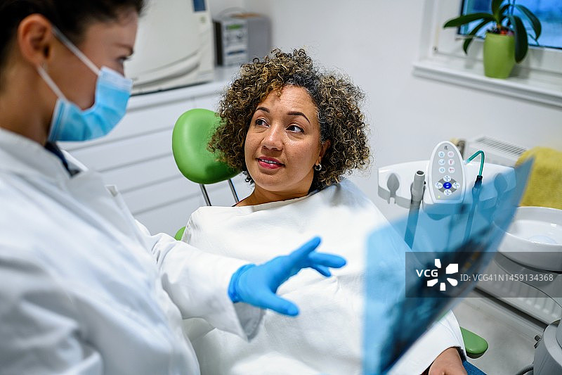 牙医向女病人解释牙齿x光片图片素材